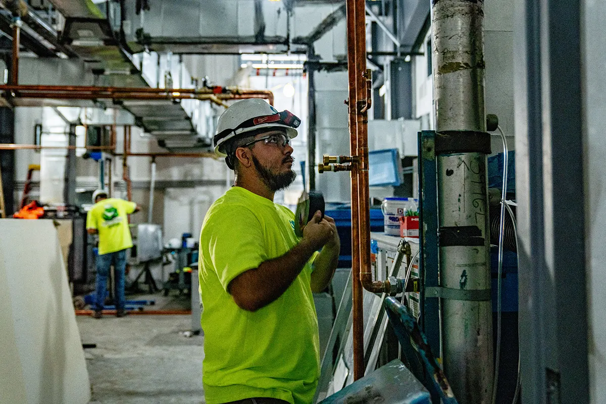 CCS crew member at work next to a piping run